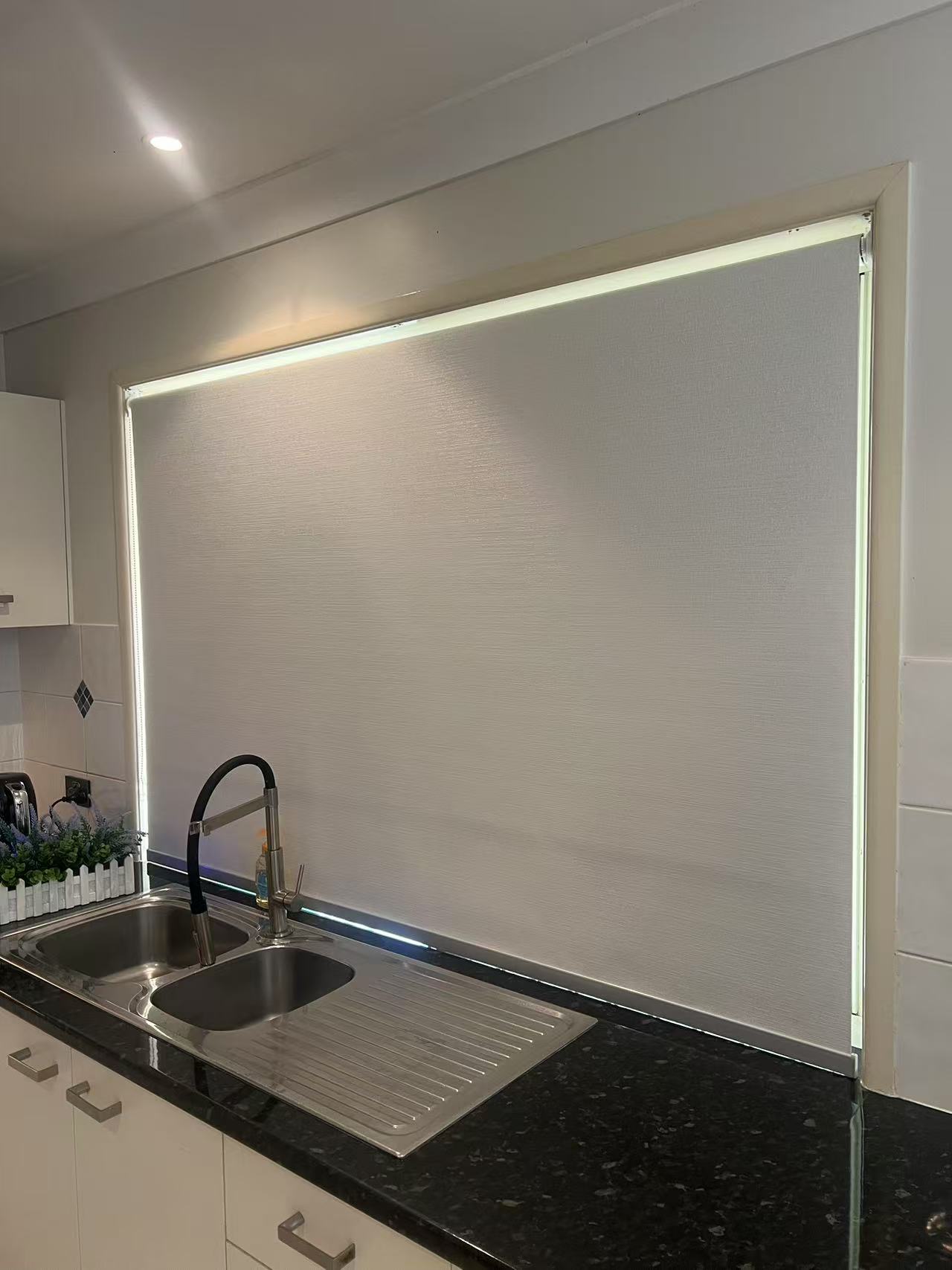 Grey blockout roller blind installed in frame for kitchen window