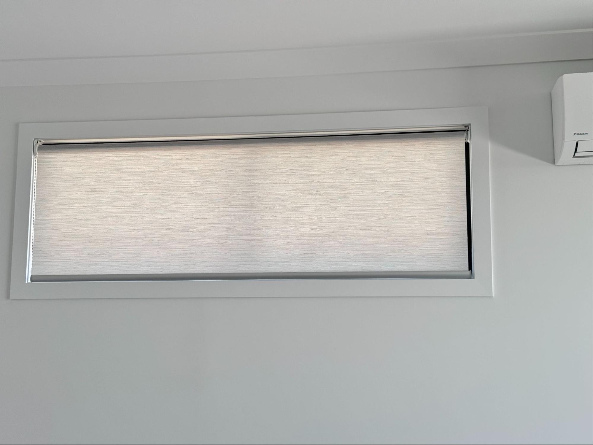 Light filtering or semi blockout grey roller blinds installed in a living room