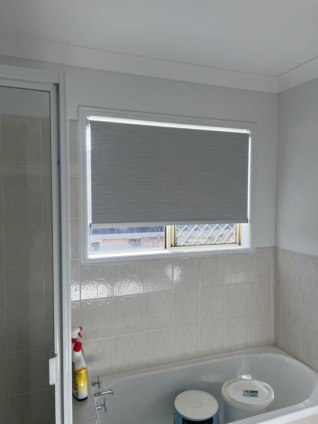 Grey blockout roller blind installed in the bathroom