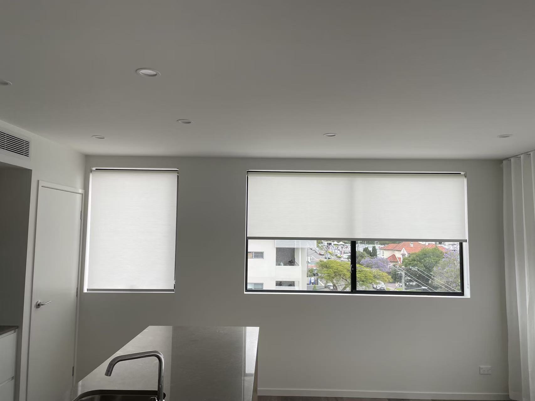 Windows installed with white filtering privacy roller blinds in the kitchen