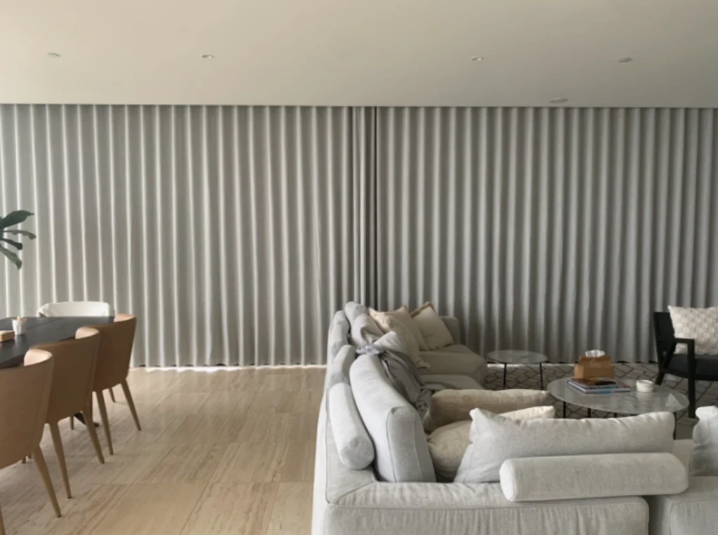 Made-to-measure curtains hanging in even folds across a full wall